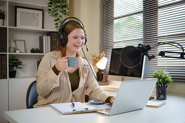 istock Young woman hosting a podcast from home, speaking into a microphone with coffee in hand. 2232809438