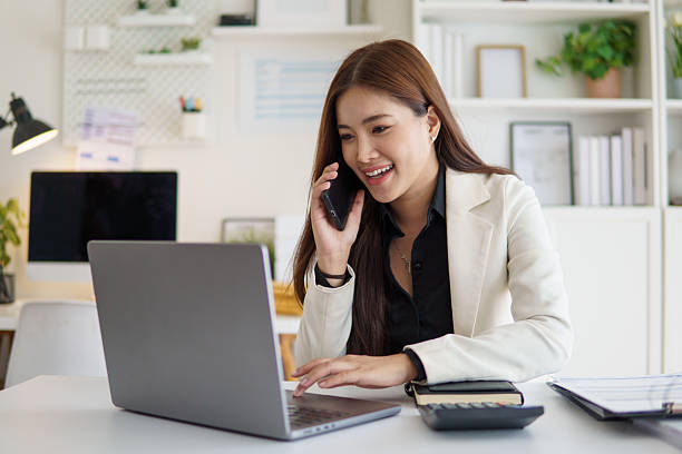 istock Confident female entrepreneur talking on the phone while working with laptop at office desk. 2232809729