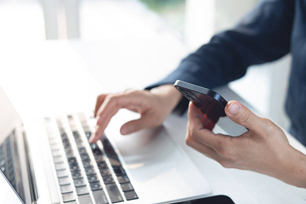 istock Business woman using smartphone and working on laptop computer with digital tablet on office table. Businesswoman surfing the internet, web browsing via laptop and searching the information, closeup 2232809781