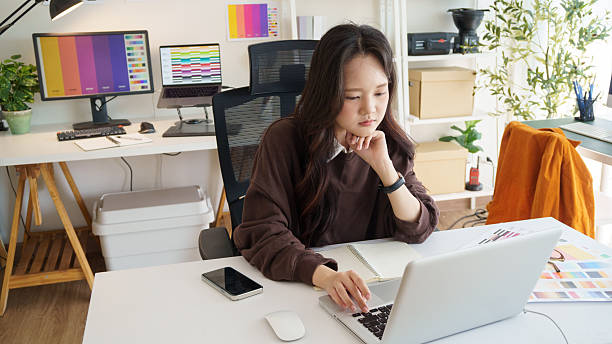 istock Young female graphic designer working on a laptop at a modern creative studio. 2232810502