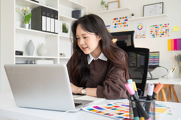istock Young female graphic designer working on a laptop at a modern creative studio. 2232810507