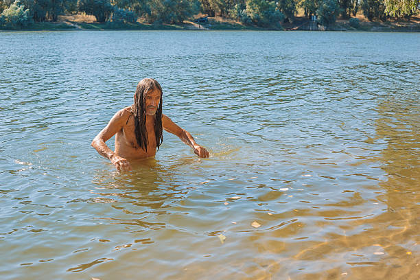 Elderly man emerging from a river after a swim on a sunny day