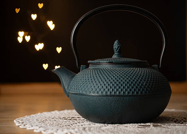 A traditional cast iron teapot on a lace doily with warm heart-shaped bokeh lights in the background.