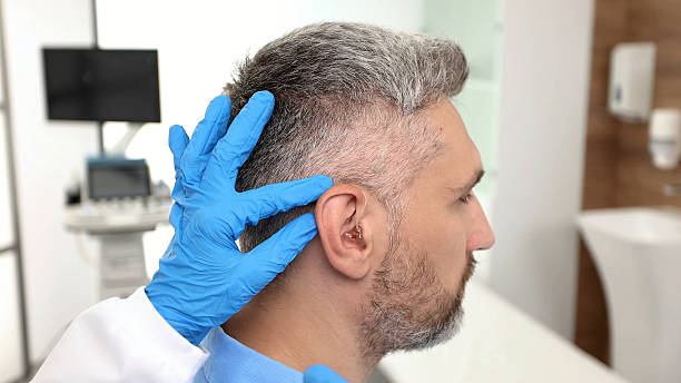 istock Installation hearing aid on man's patient ear at hearing clinic, close-up, side view. Deafness treatment, hearing solutions 2232826837