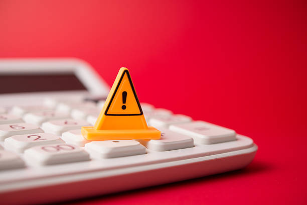 istock Yellow warning sign on white calculator with red background copy space. 2232833832