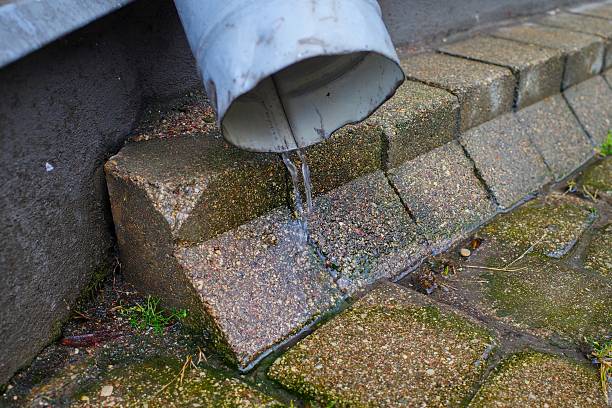 istock Water flowing from metal drainage pipe onto pavement 2232837439