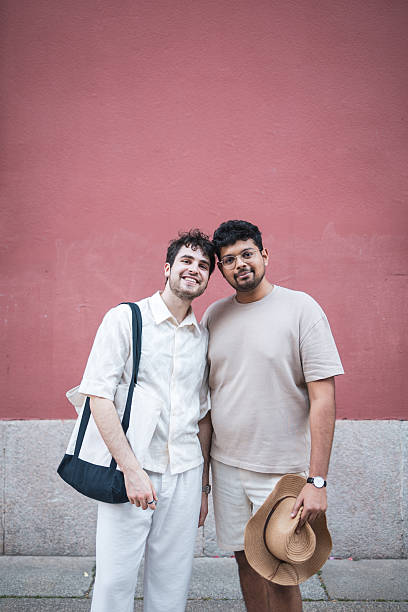 istock Two young men smiling together in front of pink wall 2232842119