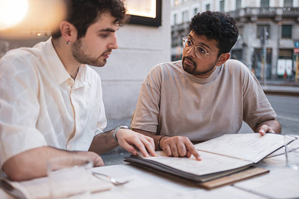 istock Two young men choosing from a restaurant menu outdoors 2232842136