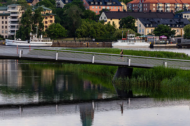 Stockholm, Sweden July 2, 2025 A woman runs over a bridge in the Hammarby Sjostad district.