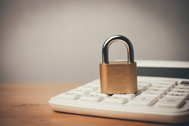 istock Padlock and white calculator on wooden table with white wall background copy space. 2232845736