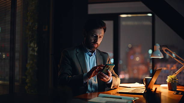 istock Man freelancer typing laptop checking cellphone at dark apartment alone closeup 2232846873