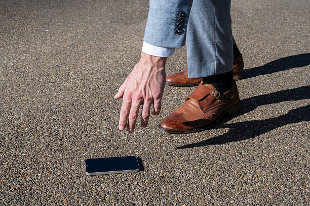istock Businessman picking up lost mobile phone from the ground 2232849015