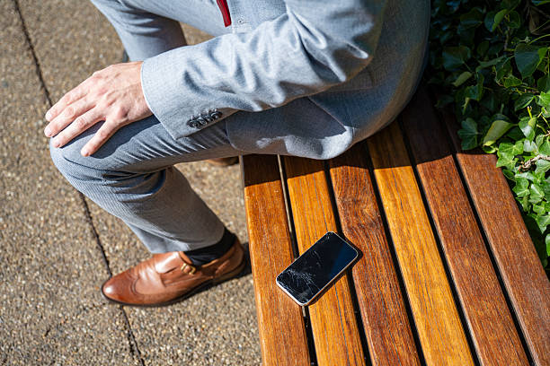 istock Businessman sitting on bench next to broken mobile phone 2232849200