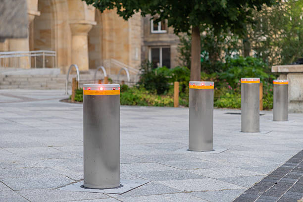 istock A row of modern retractable security bollards with red indicator lights standing on a paved urban square for public access control and safety 2232852236