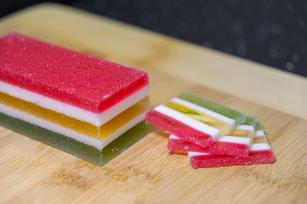 istock Colorful multi-layered gummy candy block and sugar-coated sweet slices displayed on a rustic wooden board, perfect for dessert, snack, and festive treats 2232852846