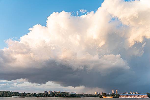 istock Dark, dense clouds filling upper half of image distant urban landscape suggested by silhouettes warm, low sun casting glow and shadows minimal detail on flat landscape no specific location identi 2232856145