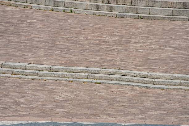 istock An architectural space features a stone staircase leading to an elevated platform, possibly a stage or viewing area The irregularly shaped paving stones below are of earthy tones The scene is natur 2232856368