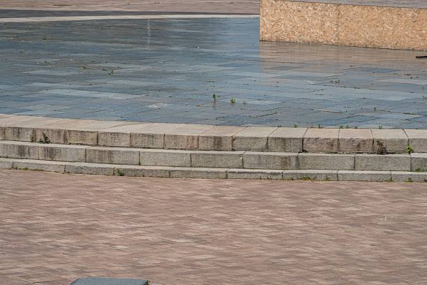 istock Tranquil outdoor scene with a curving brick pathway and weathered grey stone wall, contrasting tiled area in browns, beiges, and greys, soft diffused lighting, muted naturalistic colors 2232856397