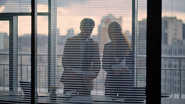 istock Two confident partners discussing contract papers standing at office window 2232856493