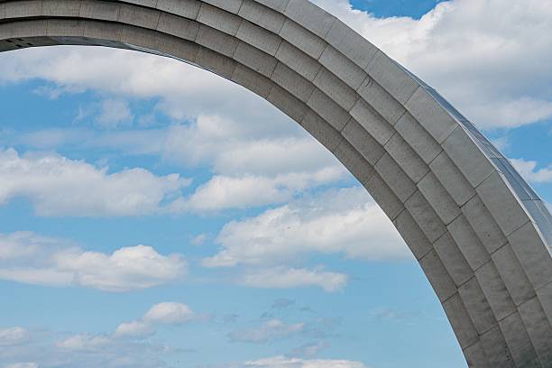 Modern concrete or steel archway structure with multiple tiers, set against a partly cloudy sky Clean lines and repetitive pattern on the structure No text or branding visible Candid photograph ca