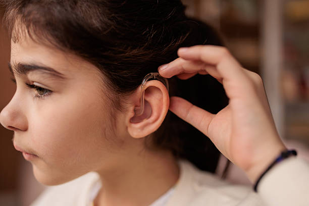 istock Little girl putting on hearing aid 2232858220