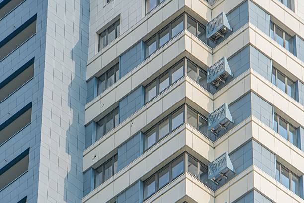 istock Modern high-rise building with a tinted, windowed facade displaying a grid pattern The structure features balconies or terraces and is mainly grey, with shadows suggesting early morning or late afte 2232858296