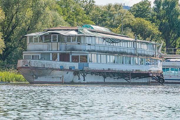 istock Multi-storied passenger boat docked at a pier, possibly for sightseeing or cruising Attached platform for boardingmaintenance Overcast sky Weathered, older vessel with signs of rust and wear 2232860836