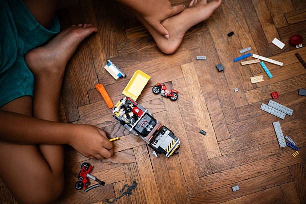 Kid assembling colorful plastic bricks on a wooden floor, developing creativity and fine motor skills