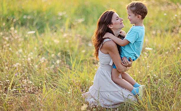 istock Happy Mother and Son Sitting Outdoors in a Sunny Field 2232863578