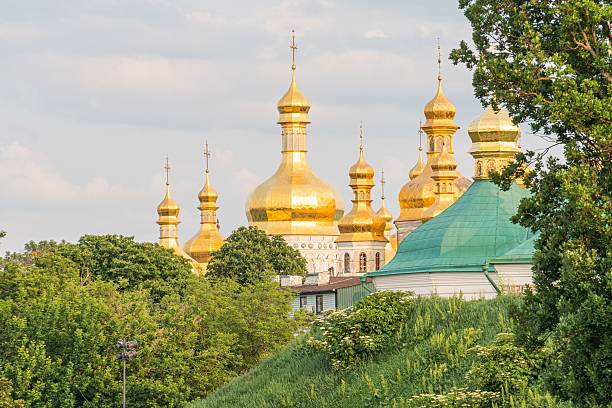 istock Large religious complex with multiple golden-domed buildings and a smaller green-roofed one, surrounded by greenery and clear skies 2232865390