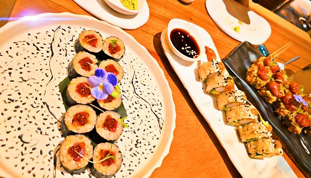 Delicious assortment of Japanese sushi rolls served on elegant plates with soy sauce and wasabi. Freshly prepared gourmet Japanese cuisine presented in a fine dining restaurant setting, perfect for concepts of Asian food, luxury dining, Japanese culture, gastronomy, fusion cuisine, and lifestyle.