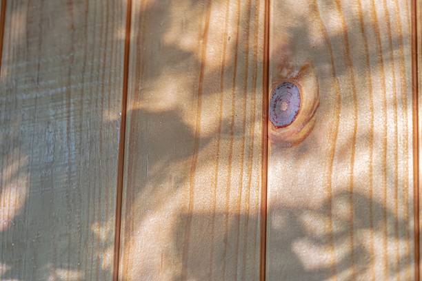 istock Close-up of weathered wooden surface under foliage, with intricate sunlight patterns and emphasized graintexture Outdoor setting suggested by shadows cast from leaves or branches Realistic style, 2232867106