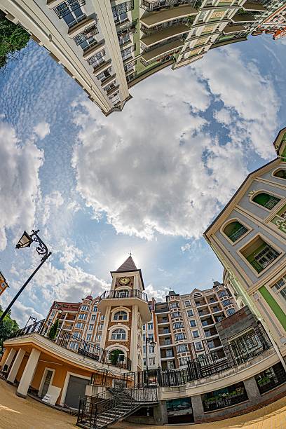 Aerial view of a European town square, distinct architectural structures with various colors, clear blue sky with scattered clouds, tranquil atmosphere, intricate details, old European city