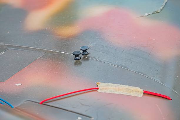 Close-up of three objects in an industrial setting two round discs with dark centers and lighter edges, possibly adhesive a longer red cylindrical object Objects rest on a flat surface under natur