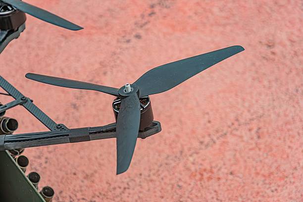 Top-down view of a black military mini drone with a metallic structure, spinning propellers