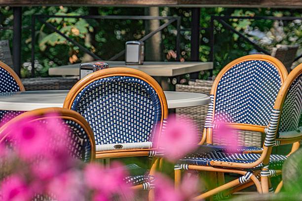 istock Outdoor dining area in a modern city, white dot patterned chairs, blue dotted backrests, white tablecloth, plates, glasses, soft lighting, warm glow, garden or patio, greenery, well-maintained surrou 2232870094
