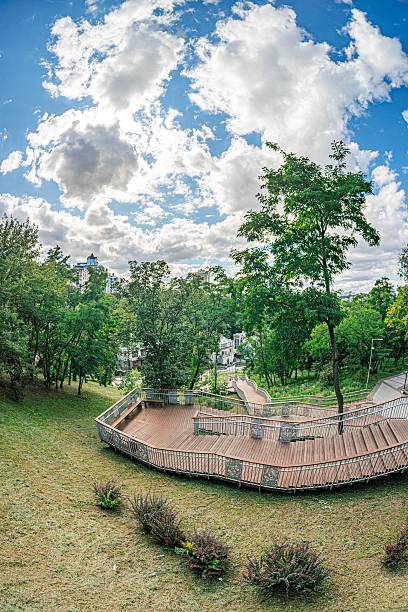 istock Partly cloudy urban park with a circular stone amphitheater surrounded by lush greenery, filtered sunlight a 2232870143