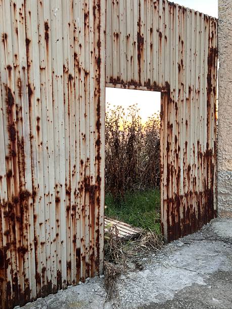 istock rusty gate leading to a field with dry grass 2232873323