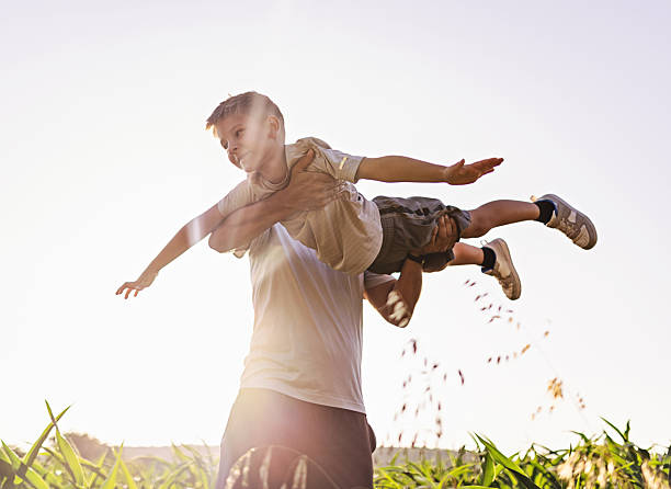 istock Father Playing Outdoors With Child at Sunset in a Field Setting 2232876839