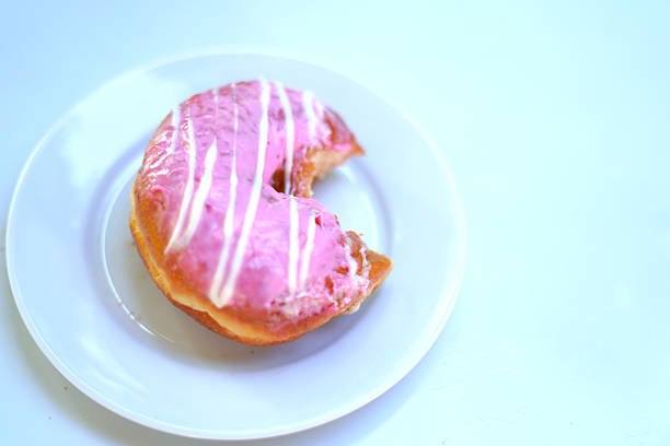 Freshly Baked Bite pink Donut Served on White Plate.