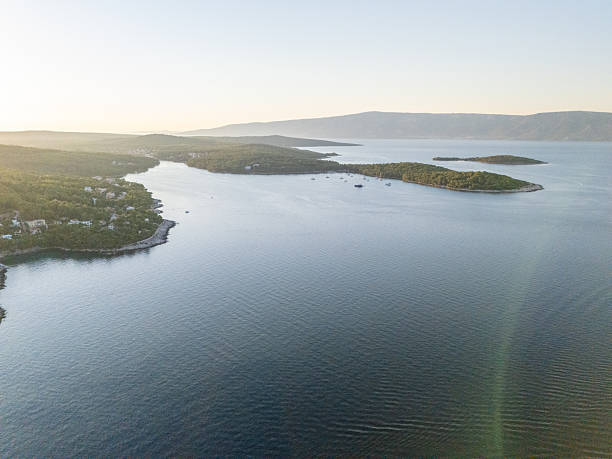 A stunning hillside view reveals an expansive landscape filled with lush greenery, showcasing the harmony between nature and topographical features in a golden hour light.