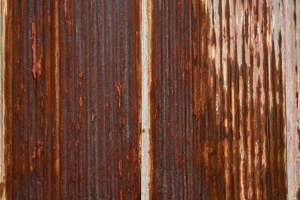 istock Close-up of an old corrugated iron sheet with peeling paint and brown rust. 2232879727