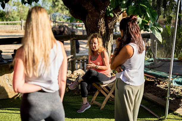 istock Three women engaging in a group therapy session outdoors, guided by a professional counselor in a serene garden, fostering emotional support and connection 2232882869