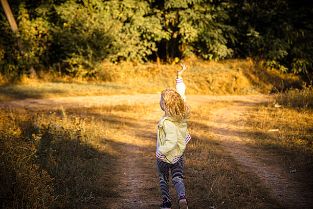 Joyful little girl enjoying exploring nature with her playful kids happy smile in green forest