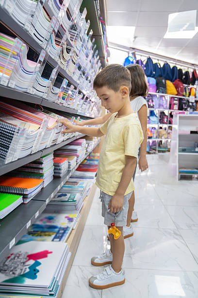 istock Elementary School Child standing in bookstore and looking for notebooks and books. Back To School Shopping Concept. Shopping for school. Little boy trying to decide which notebook to buy. 2232888781