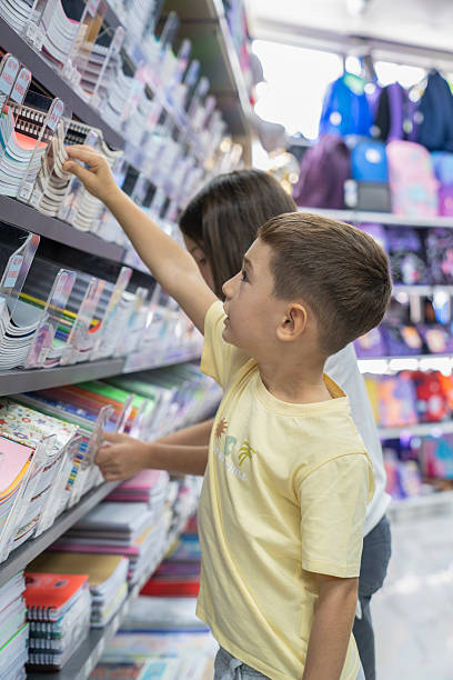 istock Elementary School Child standing in bookstore and looking for notebooks and books. Back To School Shopping Concept. Shopping for school. Little boy trying to decide which notebook to buy. 2232889705