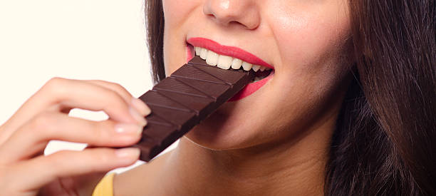 istock Young woman eating chocolate bar 2232891162