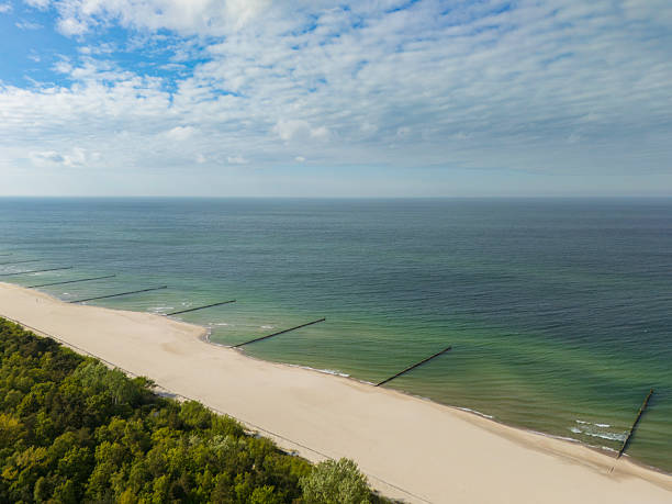A picturesque beach featuring a sandy shoreline with gentle waves and a vibrant blue sky. Perfect for conveying concepts of tranquility, ocean nature, seaside vacations, and serene environments. The image effectively portrays relaxation and natural beauty, ideal to inspire travel or leisure-related ideas.