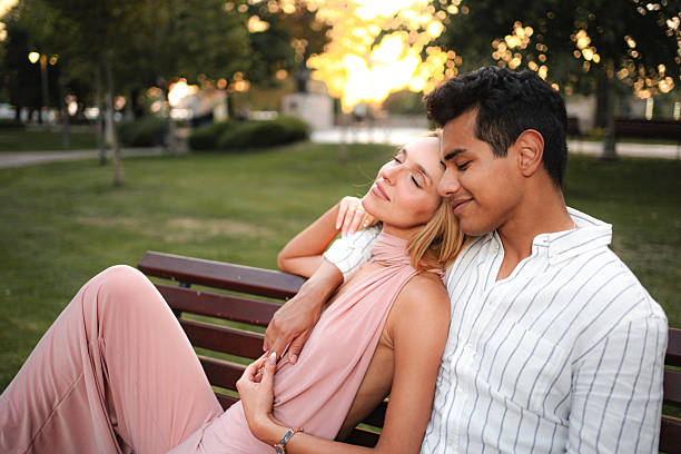 istock Young couple relaxing on bench in park at sunset 2232897798