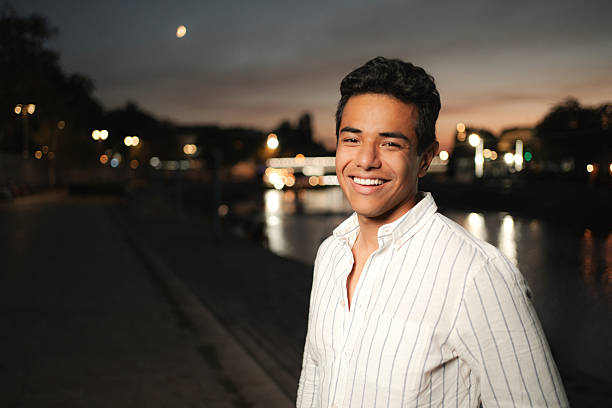 Portrait of a cheerful young man smiling at camera in a city at night